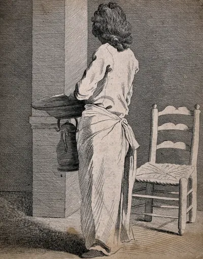 A barber with his back turned, standing by his chair