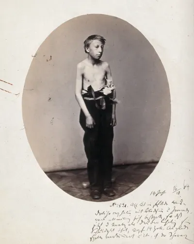 A boy, standing, viewed in full length, naked to the waist