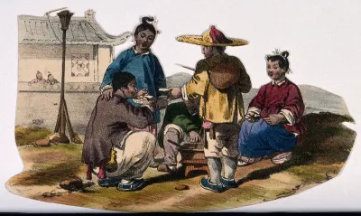 A Chinese family sit around a small cooking stove eating by the side of the road