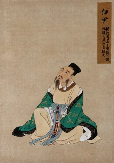 A Chinese figure, seated, wearing emerald green coloured silk robes with a black
