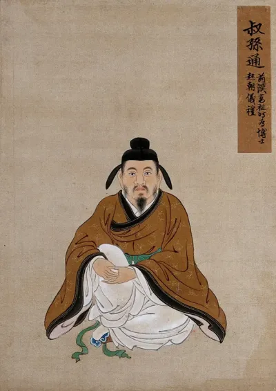 A Chinese figure wearing light brown silk robes with a dark brown border