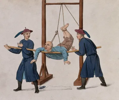 A Chinese man is hanging up from a rope attached to a wooden structure and resting on a bamboo stick held by two Chinese men
