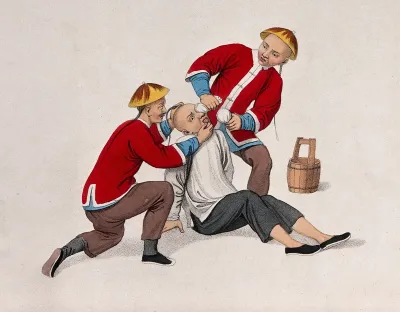 A Chinese man is held on the ground by a man while another is burning his eyes with lime