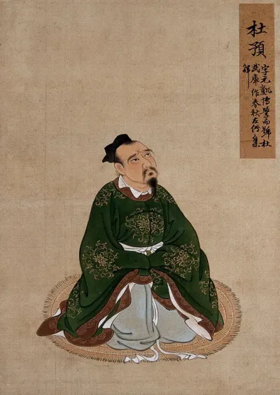 A Chinese seated figure in green silk with brown border