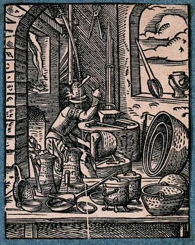 A coppersmith is surrounded by items he is making, including pans, cauldrons and jugs