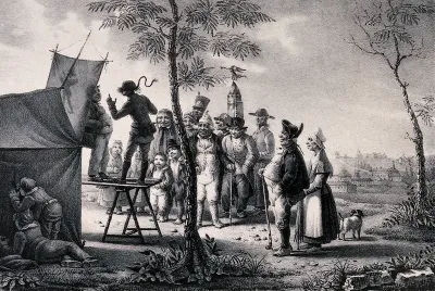 A crowd of people have gathered to watch two men performing on a table in front of a tent; children are peeping through the canvas from the side