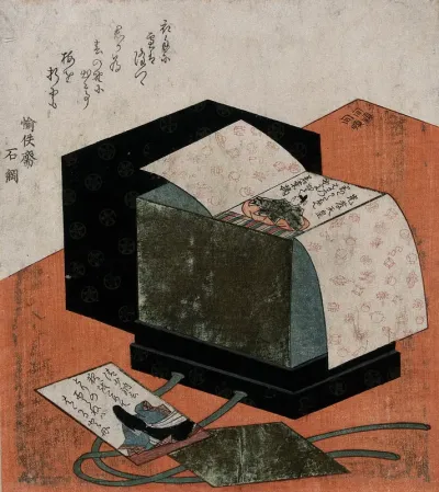 A lacquer box containing a set of poem cards, on a red table: the box is opened to reveal a stack of cards