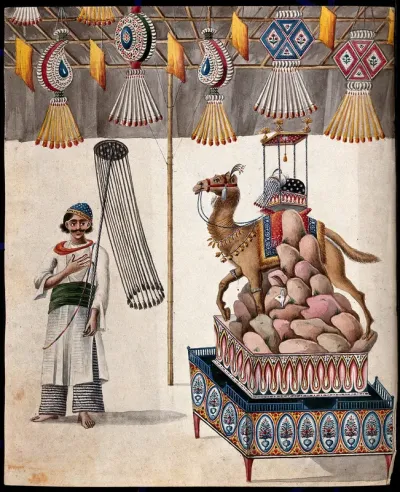 A man carrying a ceremonial object stands next to a tableau of rocks, a camel, decorated headgear and other animals set on an ornate base