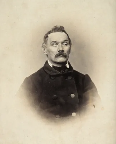 A man, head and shoulders; his left eyelid is heavy and his right eye is raised