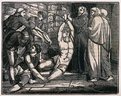 A man in a loincloth is tied to a wall by his wrists having his flesh pierced with pliers while three monks look on