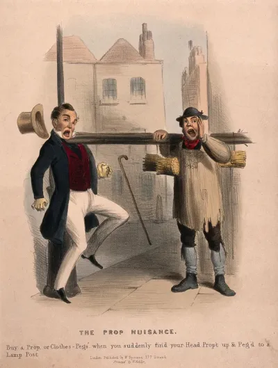 A man is pinned against a lamp post by the clothes-props that a street trader is selling