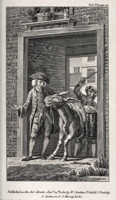 A man is trying to persuade a donkey with kindness to pass a gate while another man hits the back of the animal with a stick