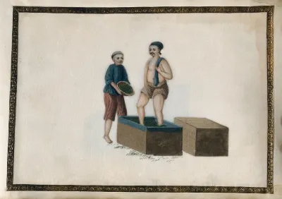 A man packs tea leaves down into a large wooden crate by stamping them with his feet; another pours more tea leaves into the crate