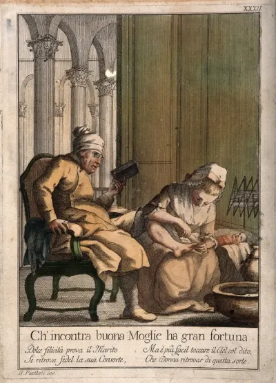 A man reads a book while his wife cuts his toenails