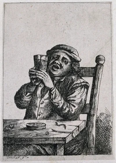 A man sits at a table with a drink and discarded pipe