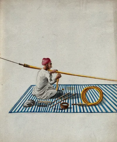 A man sitting on a carpet making hookah pipes