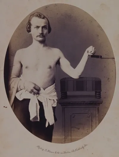 A man, viewed from the front and naked to waist, leaning on a cushion