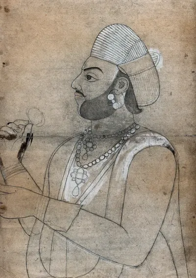 A man wearing a turban and jewellery, holding a flower (?)