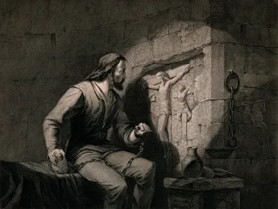 A prisoner sits in his cell and carves the Crucifixion in the wall with a nail