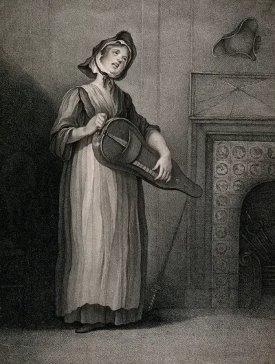A Savoyard girl standing near to a fire place playing the hurdy-gurdy