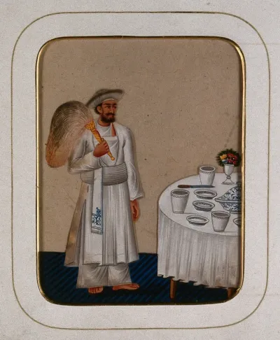 A servant standing next to a dining table, holding a fly whisk