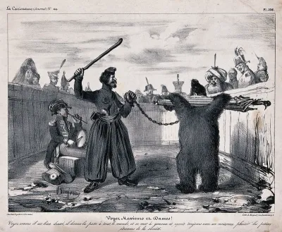 A soldier plays a drum as a man with a chained bear with its arms held back by an umbrella is making it dance to entertain the crowd