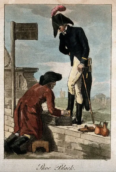 A soldier stands on a wall as a man cleans his boots