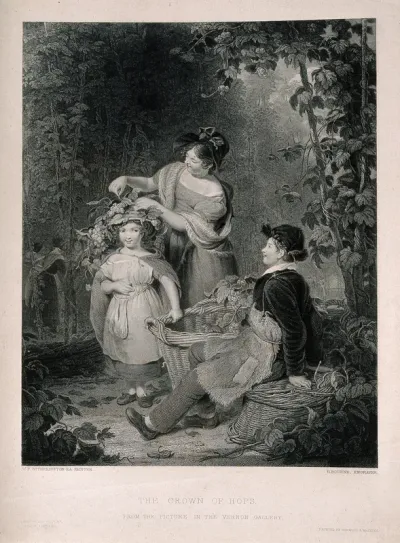 A woman decorating a girl's hat with hops in a hop field during harvest