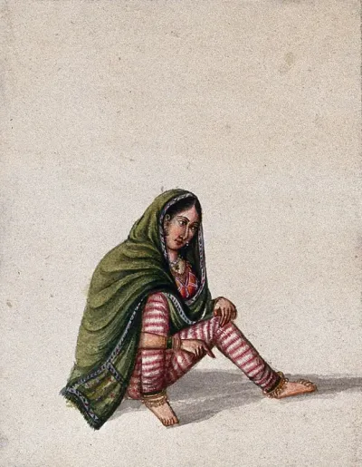 A woman in a green chunni (scarf) sitting and pointing to the ground
