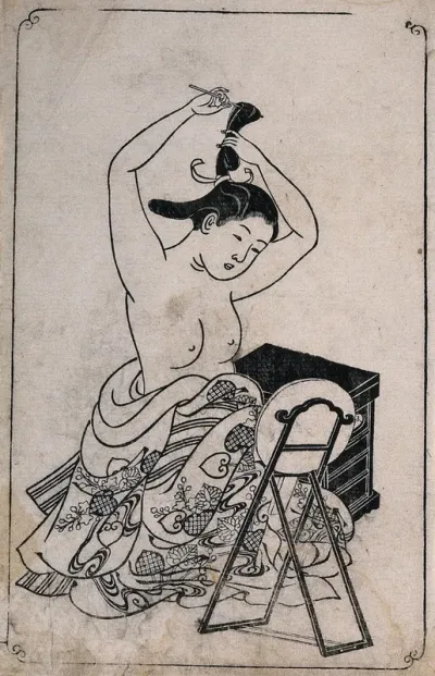 A woman, naked to the waist, dressing her hair before a mirror stand