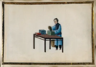 A woman packing tea leaves into small brightly painted wooden boxes
