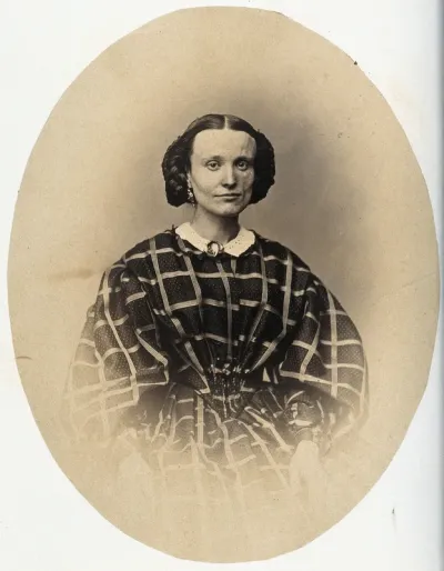 A woman seated; the left side of her face appears slightly deformed
