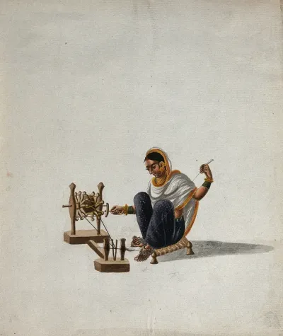 A woman sitting on a low stool and spinning thread