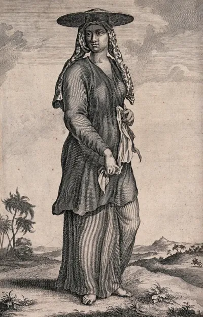 A woman slave in Bali, standing with a cloth in her hands and a wide hat on her head