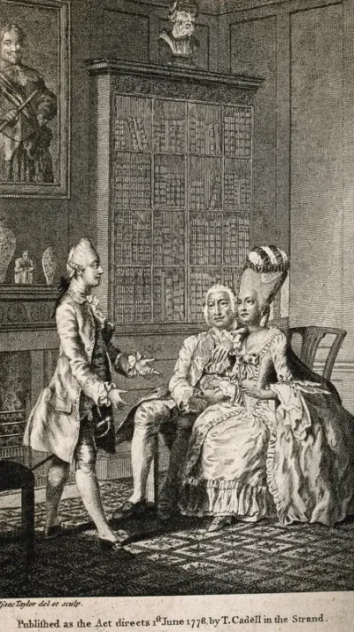 A woman with an extremely high wig seated next to a male companion; they both watch a young man who appears to be acting