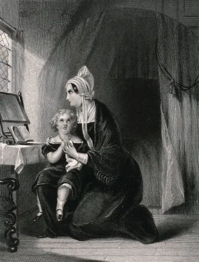 A young child and its mother sit together saying prayers