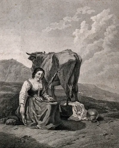A young woman sits on a mountain side with a cow and a basket on the ground, spinnning yarn