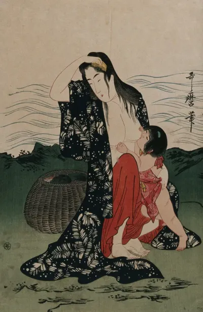 An ama (woman diver) on shore combs her wet hair while breast feeding a toddler