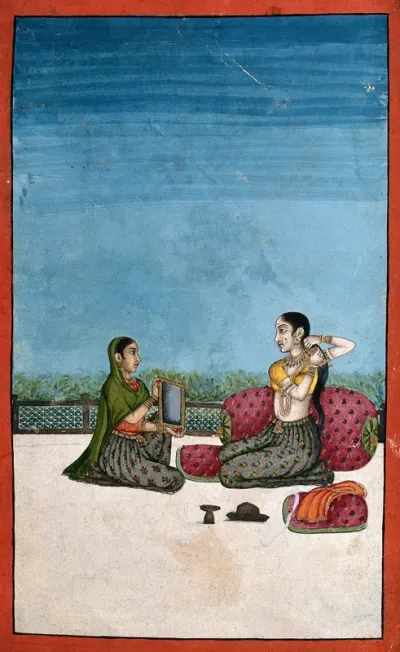 An Indian lady attending to her toilette with a helper holding a mirror for her