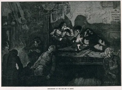 An opium den in London's East End with smokers lying on wooden bunks and slouching by the fire