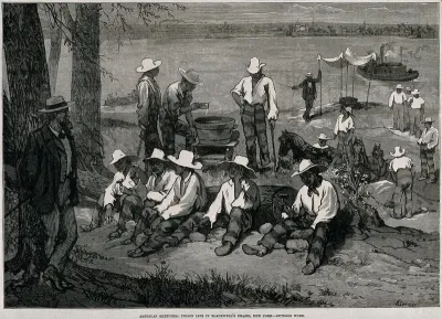 Blackwell's Island Penitentiary, New York: prisoners in chains are working with hammers breaking stones on the side of the roadway, a guard in a jacket and trousers with a cane is watching over them from under a tree
