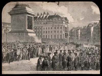Chelsea Pensioners in a procession in Trafalgar Square, heading towards the Strand, to the left the base of the Nelson Column, fenced-off
