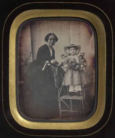 Child Standing on a Chair Holding Flowers, with Mother