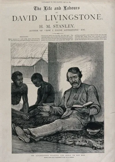 David Livingstone, seated on the ground, reading from the Bible to two African followers