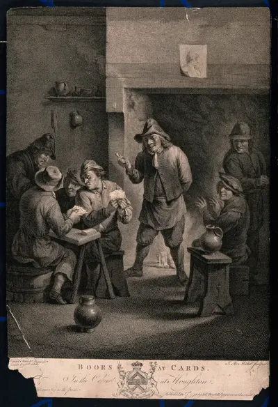 Four men sit at a table playing cards, others watch as they stand around a fire