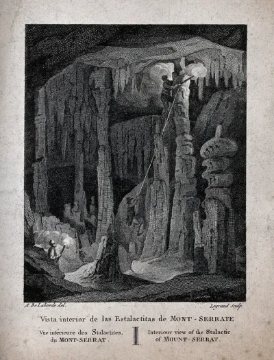 Geology: visitors climbing the large stalactites in a cave at Montserrat