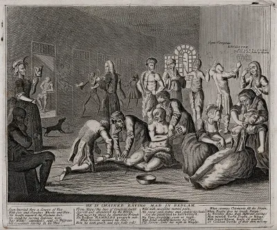 In a lunatic asylum, and in the company of a variety of other deranged individuals, a half-naked Ramble Gripe, his wrists chained, is restrained by orderlies