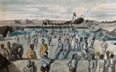 India : a gathering of Hindu ascetics (sadhus) at a religious festival: in the background, the Union flag flies over a British military fortification