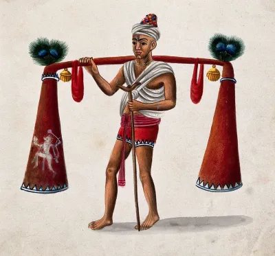India: a man with a crutch carrying tubes decorated with bells and peacock feathers