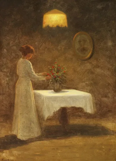 Interior with a woman arranging a bouquet of red flowers on a table.